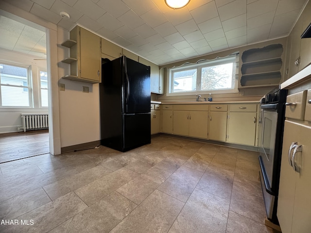 kitchen with radiator, cream cabinets, and black refrigerator