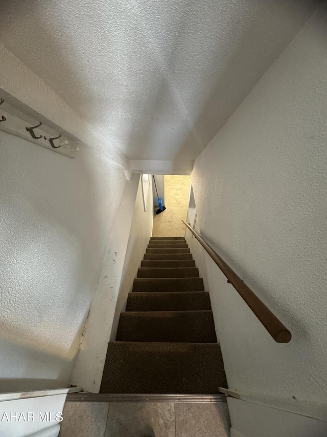 stairway featuring a textured ceiling