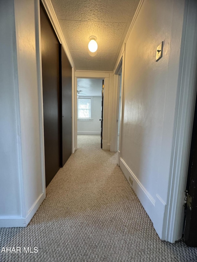 hallway featuring light carpet and a textured ceiling