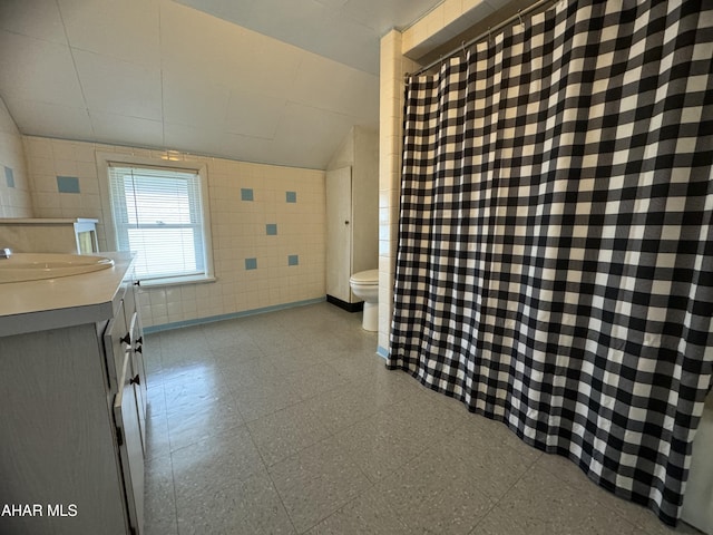 bathroom featuring vanity, toilet, and tile walls