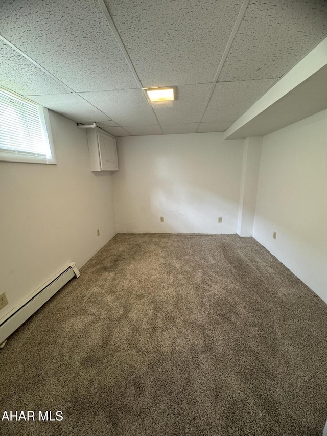 basement with a paneled ceiling, carpet, and a baseboard radiator