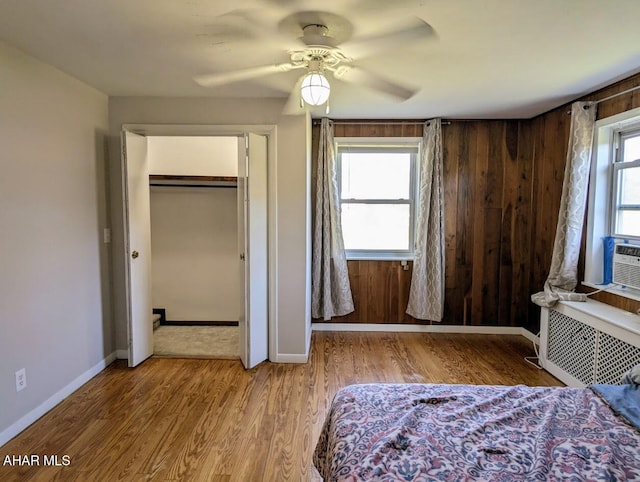 unfurnished bedroom featuring hardwood / wood-style floors, ceiling fan, radiator heating unit, and multiple windows