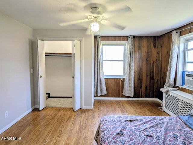 unfurnished bedroom featuring radiator, ceiling fan, light hardwood / wood-style floors, and multiple windows