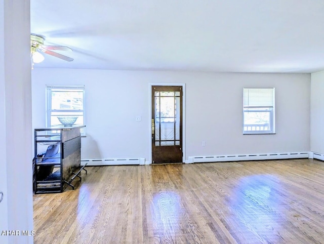 unfurnished room with light hardwood / wood-style floors, a wealth of natural light, and a baseboard heating unit