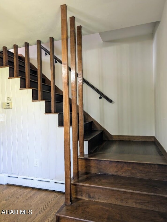 stairway with wood-type flooring and a baseboard radiator