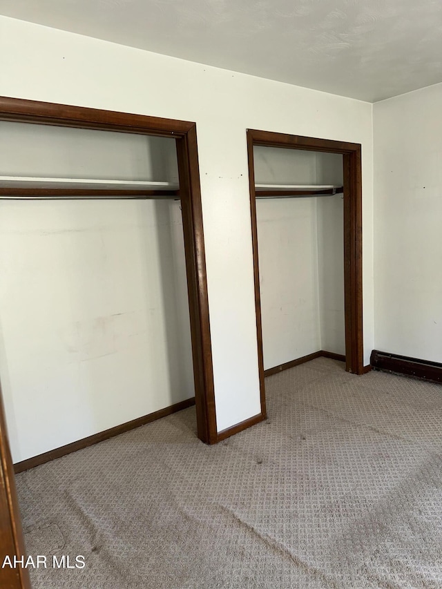 unfurnished bedroom with light colored carpet and a closet