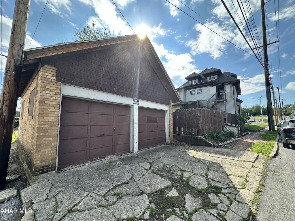 view of property exterior featuring brick siding, fence, and an outdoor structure