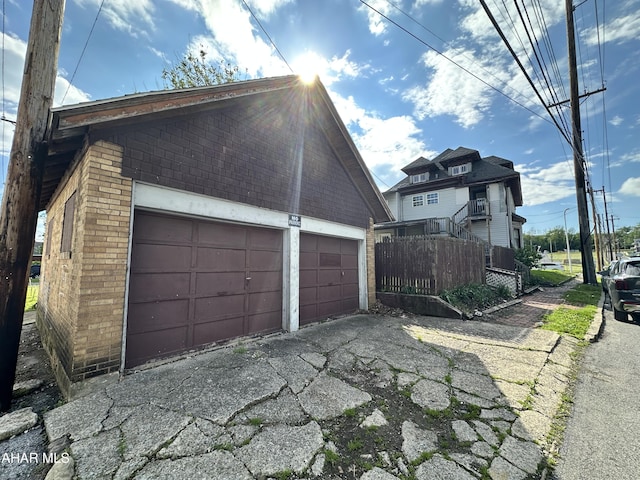 view of property exterior featuring brick siding, fence, and an outdoor structure
