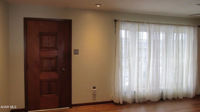 unfurnished room featuring wood-type flooring and a healthy amount of sunlight