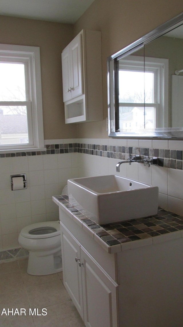 bathroom with vanity, tile walls, tile patterned floors, and toilet