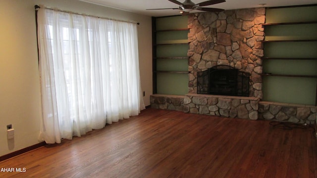 unfurnished living room featuring a stone fireplace, hardwood / wood-style floors, and ceiling fan