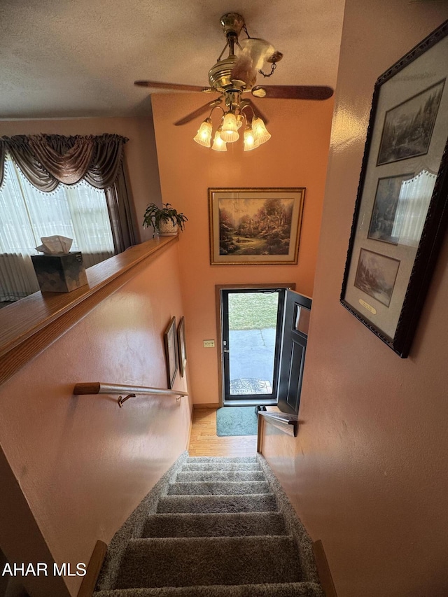 stairs featuring ceiling fan and a textured ceiling