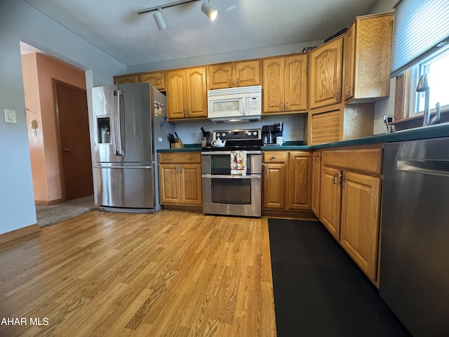 kitchen featuring light hardwood / wood-style flooring, track lighting, and appliances with stainless steel finishes