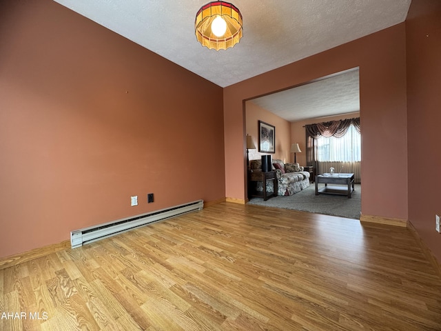 unfurnished room featuring a baseboard radiator, a textured ceiling, and light wood-type flooring