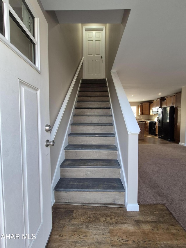 stairs featuring carpet, wood finished floors, and baseboards