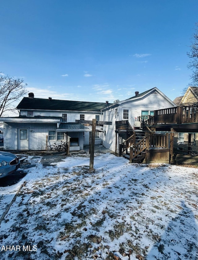 snow covered house featuring stairway and a wooden deck