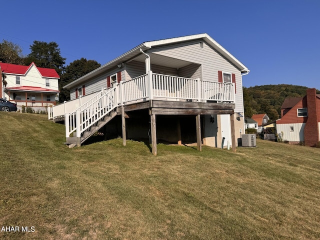 rear view of property featuring a lawn, a deck, and central AC