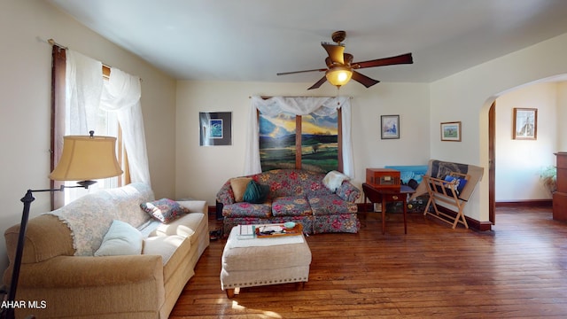 living room with baseboards, wood finished floors, arched walkways, and ceiling fan