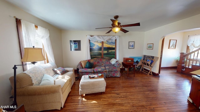 living area featuring arched walkways, baseboards, ceiling fan, and wood-type flooring