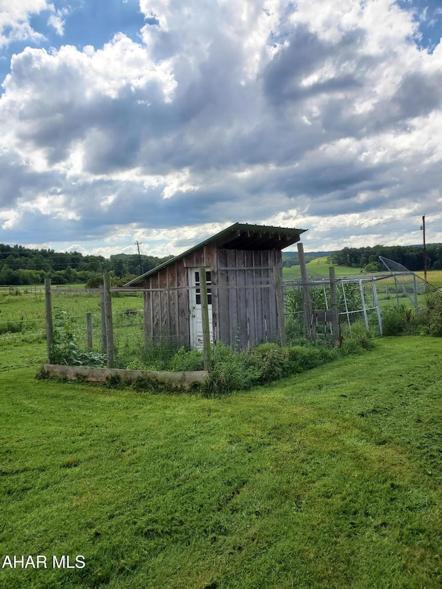 view of outbuilding with an outdoor structure, a rural view, and fence