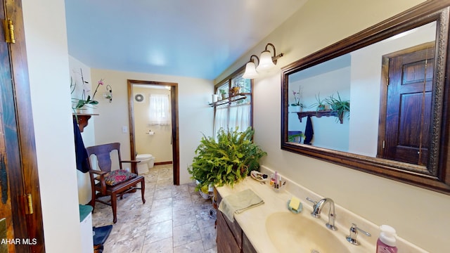 bathroom with toilet, vanity, and baseboards