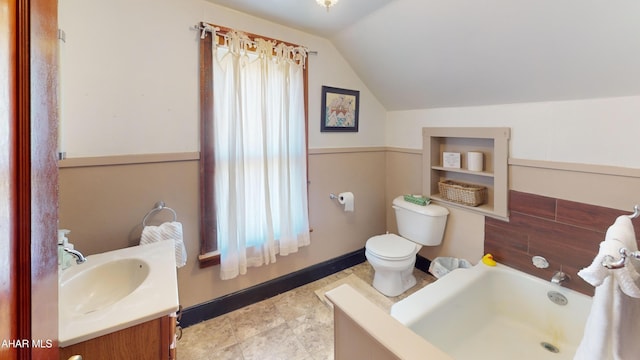 bathroom featuring lofted ceiling, toilet, vanity, and a washtub