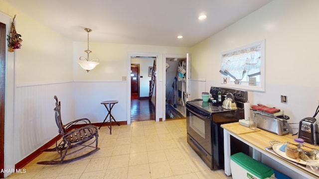 kitchen with recessed lighting, a wainscoted wall, black range with electric cooktop, and hanging light fixtures