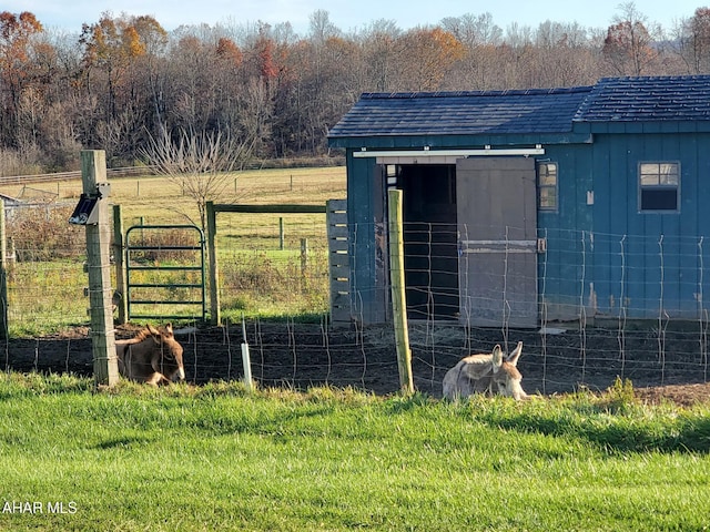 view of outbuilding featuring a rural view, an outbuilding, and fence