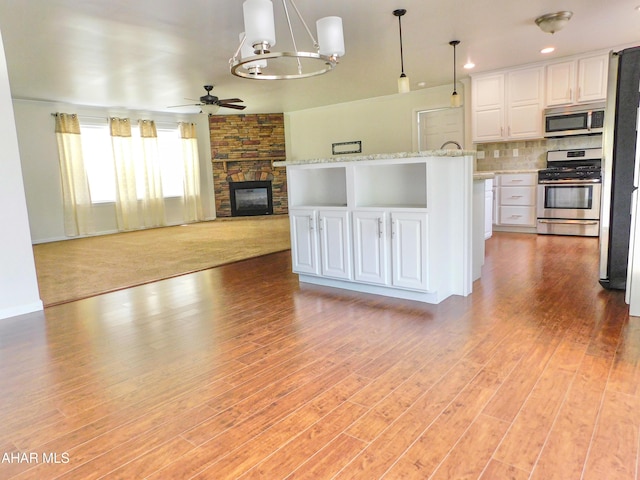 115 Spruce St, Smithmill, PA 16680 - kitchen with appliances with stainless steel finishes, ceiling fan, white cabinetry, open floor plan, and a stone fireplace