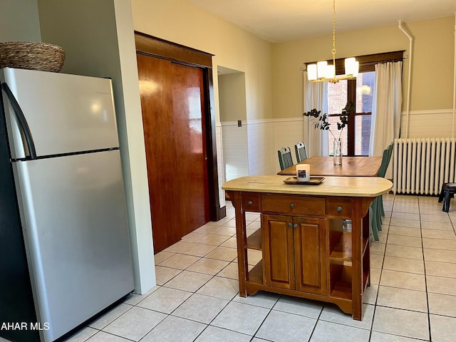 kitchen with light tile patterned floors, a chandelier, radiator, and freestanding refrigerator