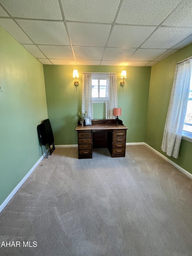 unfurnished office featuring baseboards, a paneled ceiling, and carpet