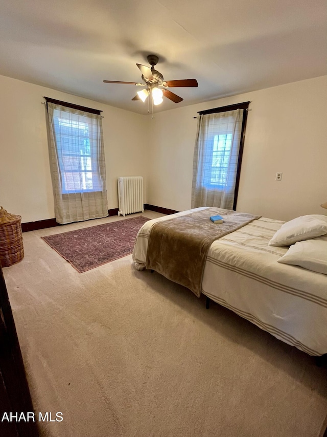 bedroom with baseboards, radiator, ceiling fan, and carpet