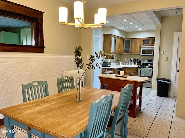 dining area with radiator, light tile patterned floors, recessed lighting, wainscoting, and a notable chandelier