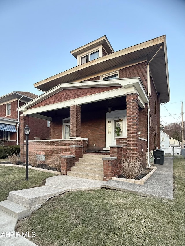 view of front of property with a porch, brick siding, and a front yard