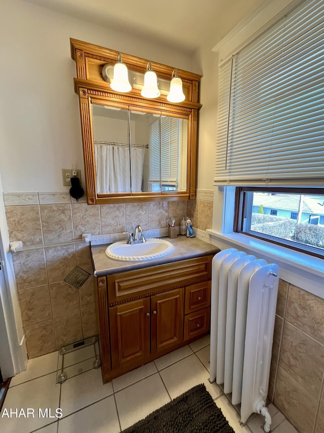 full bath featuring radiator, vanity, wainscoting, tile patterned floors, and tile walls