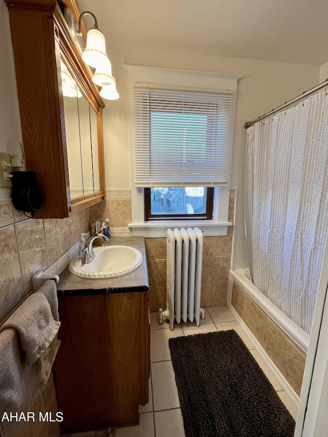 bathroom with tile patterned flooring, tile walls, radiator heating unit, vanity, and tiled shower / bath