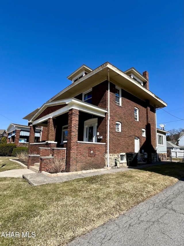 view of side of property featuring brick siding, a chimney, and a lawn