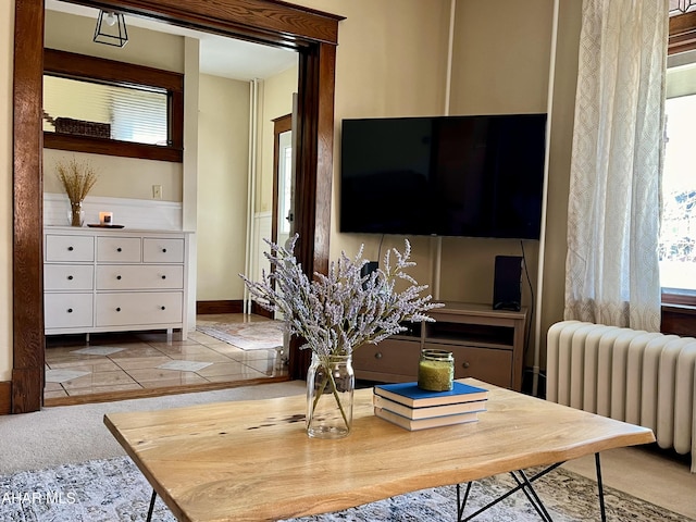 carpeted living room featuring baseboards, radiator heating unit, and tile patterned flooring