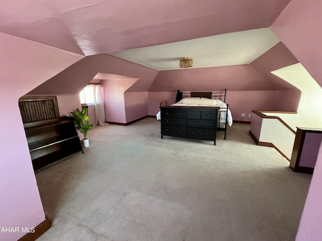 carpeted bedroom with vaulted ceiling and baseboards