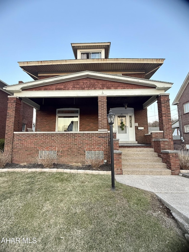 view of front facade with brick siding, a porch, and a front yard