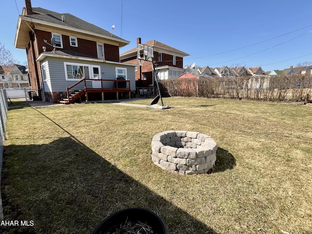 rear view of house with a wooden deck, fence, a lawn, and an outdoor fire pit