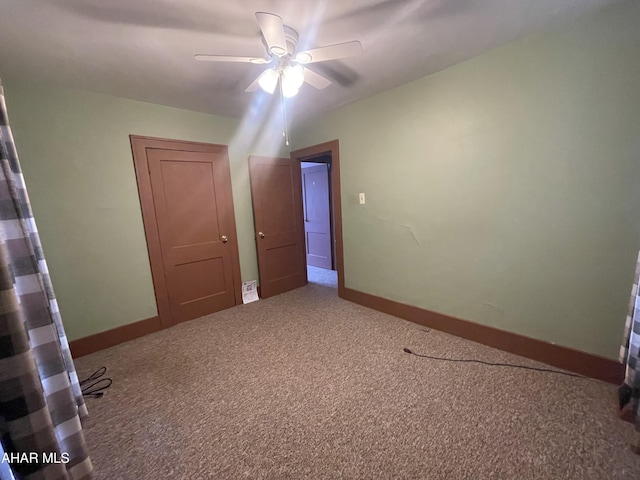 interior space featuring baseboards, ceiling fan, and carpet