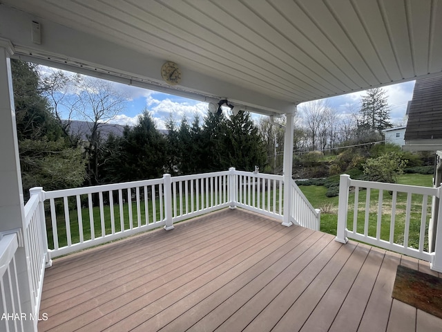 wooden deck featuring a lawn