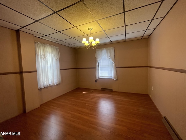 unfurnished room featuring visible vents, a drop ceiling, wood finished floors, and a chandelier