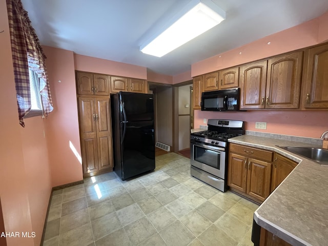 kitchen with a sink, brown cabinetry, black appliances, and visible vents