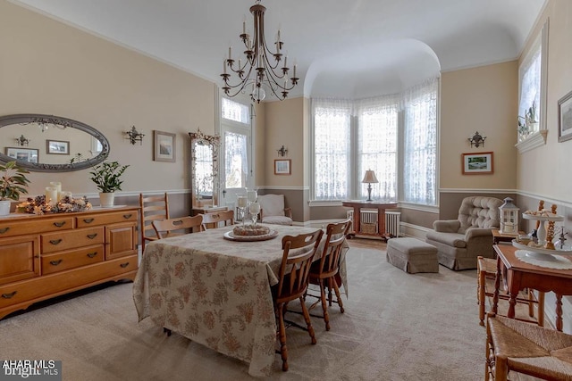 dining space with an inviting chandelier, ornamental molding, light colored carpet, and a healthy amount of sunlight