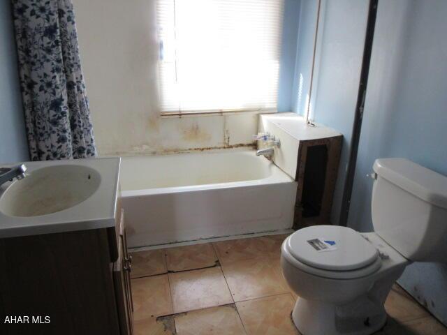 bathroom with tile patterned floors, toilet, a bathtub, and vanity