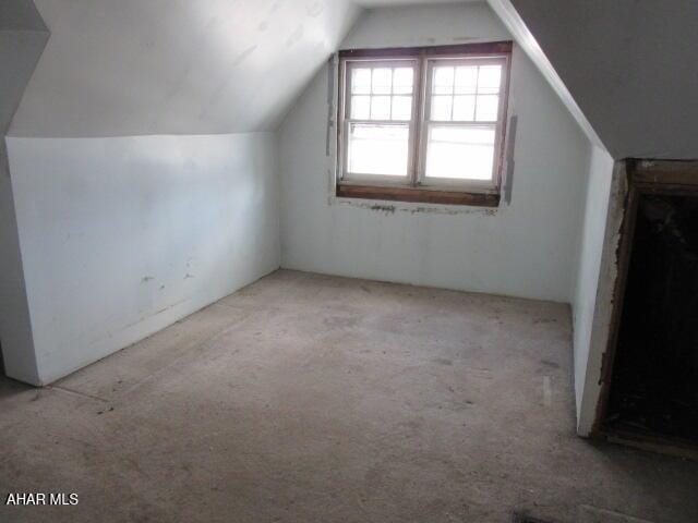 bonus room with light carpet and vaulted ceiling