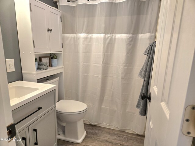 bathroom featuring curtained shower, vanity, wood-type flooring, and toilet