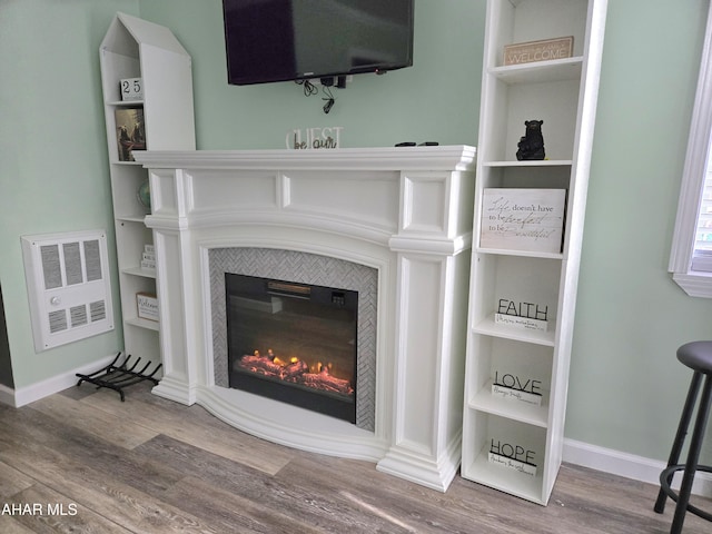 interior details with a tiled fireplace and wood-type flooring